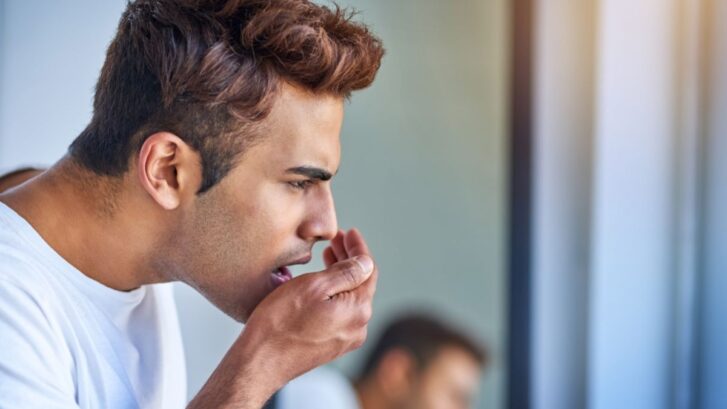 A man checking his breath in the mirror due to persistent bad breath and oral hygiene concerns.