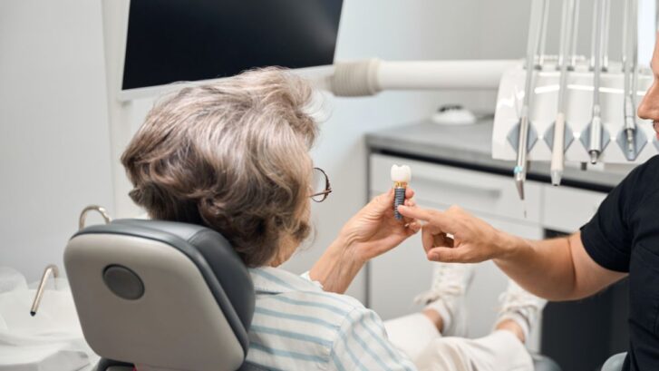 Dentist explaining dental implant to patient during consultation.