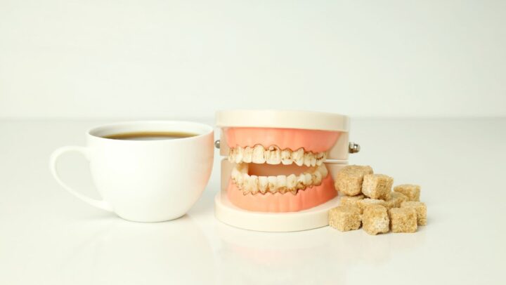 Dental model beside coffee and sugar cubes illustrating the hidden effects of sugar on teeth and oral health.